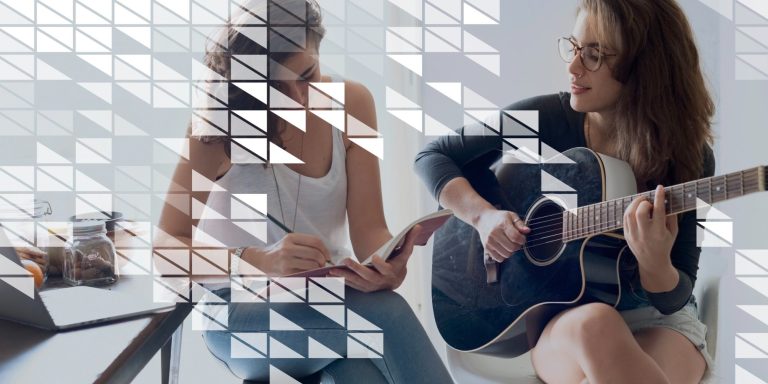 Deux femmes, l'une jouant de la guitare, l'autre prenant des notes, dans un intérieur lumineux.